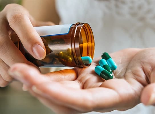 Imagem que representa deformulação de produto farmacêutico. Uma mão deixa cair um punhado de pílulas na outra, representando a análise detalhada da composição de medicamentos.